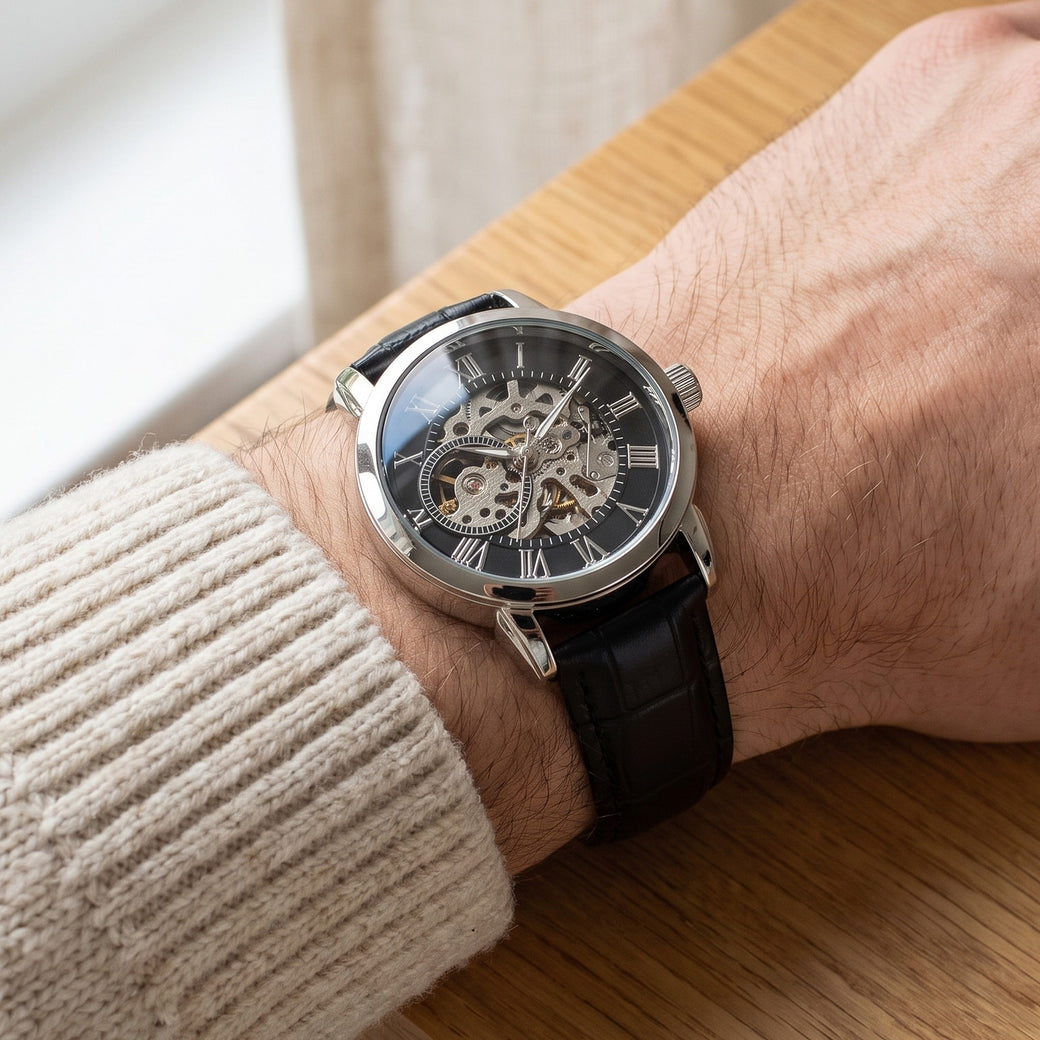 The silver openwork watch with black leather strap worn on a young man's wrist